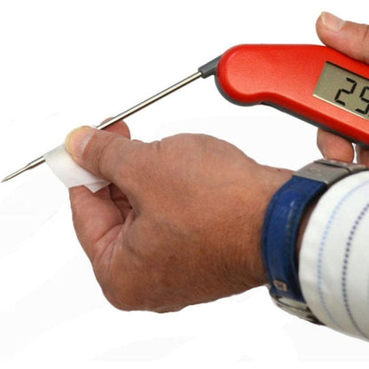 Une personne tenant un thermomètre à sonde numérique avec une poignée rouge, affichant une température de 29 degrés, à côté du Carton de 100 lingettes pour sondes en sachet unique de Thermomètre.fr.